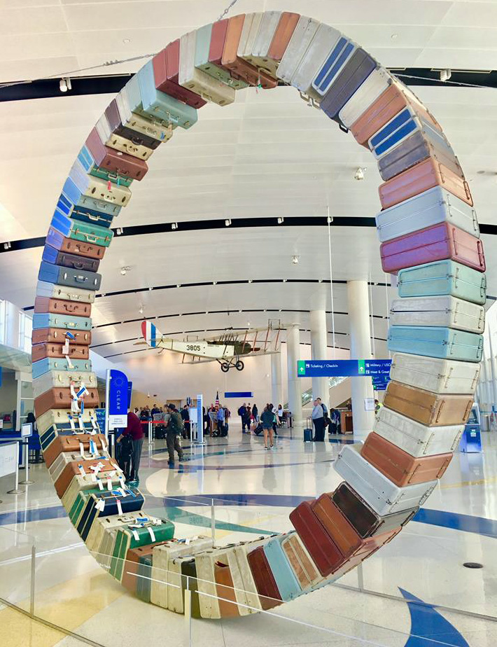 Vista del Jenny en la terminal a través de la escultura "Rueda de maletas", creada por Art Guys